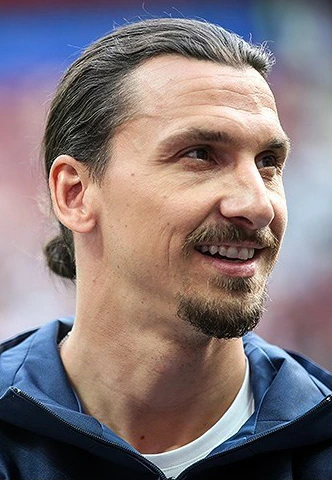 Zlatan Ibrahimović smiling in a close-up portrait at a football stadium.