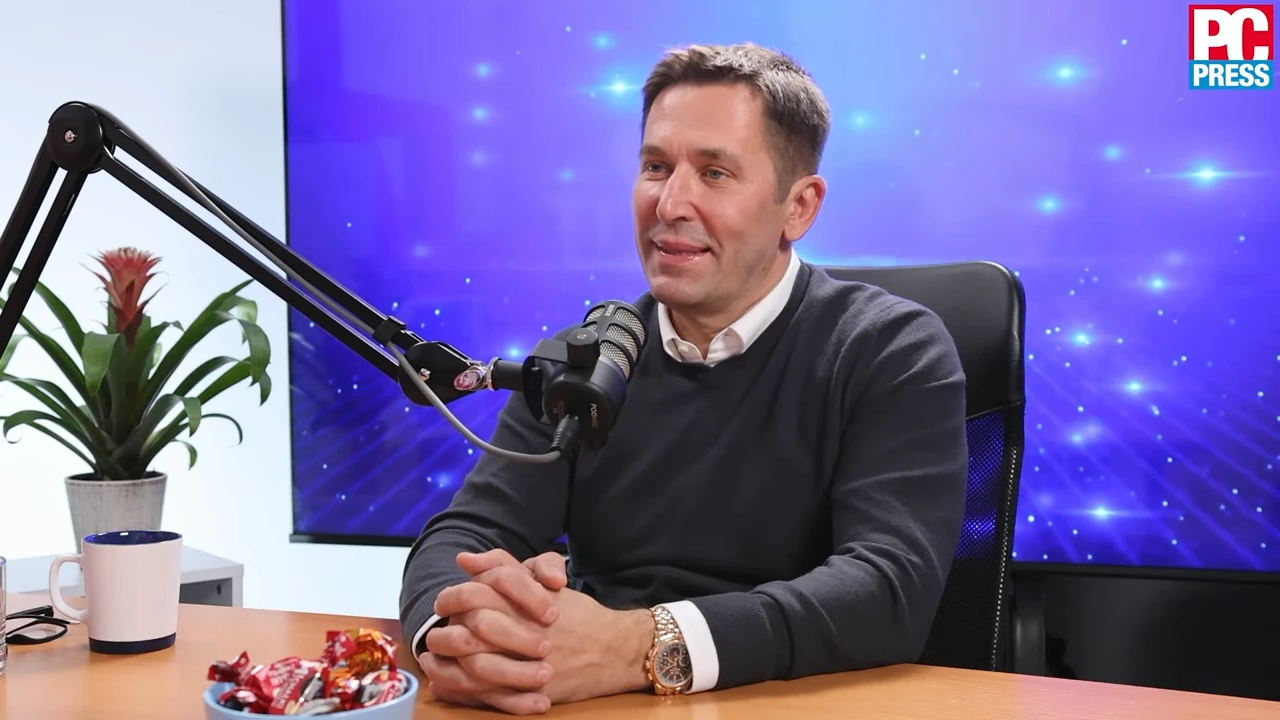 Veselin Jevrosimović speaking in a studio interview with a microphone, seated at a desk.